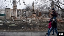 Люди проходят мимо разрушенного здания. Иловайск, Донецкая область, 27 февраля 2015 года.