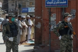 Security personnel stand guard as a few worshippers offer Friday Prayers outside a closed mosque during a lockdown in Peshawar on April 10.
