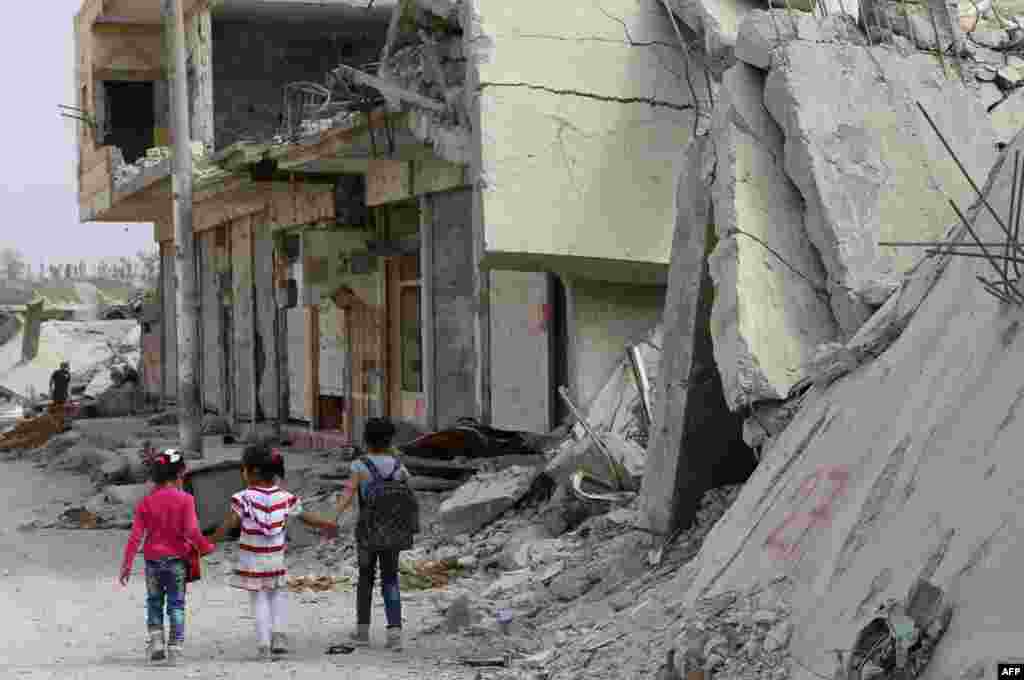 Syrian children walk past debris while heading to school on the second day of the new school year in the Kurdish town of Kobani. (AFP/Delil Souleiman)