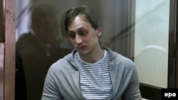 Former Bolshoi ballet dancer Pavel Dmitrichenko is seen in a glass-walled cage during an appeal hearing against the verdict passed in the case of an acid attack against Bolshoi Ballet director Sergei Filin at the Moscow city court in March 2014.