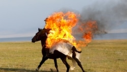 A horseback rider performs a fire stunt during a show organized for participants in the Gallops 2025 equestrian rally near Lake Song Kol in Kyrgyzstan.