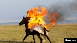 A horseback rider performs a fire stunt during a show organized for participants in the Gallops 2025 equestrian rally near Lake Song Kol in Kyrgyzstan.
