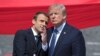 French President Emmanuel Macron (left) talks to U.S. President Donald Trump while attending the traditional military parade as part of the Bastille Day celebrations in Paris on July 14, 2017.