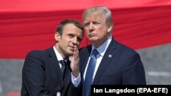 French President Emmanuel Macron (left) talks to U.S. President Donald Trump while attending the traditional military parade as part of the Bastille Day celebrations in Paris on July 14, 2017.