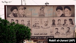 A billboard depicting Iranian spiritual leaders, top right, and volunteer fighters from the Iran-backed Popular Mobilization Forces who were killed in Iraq fighting Islamic State militants, is displayed in Basra, March 31, 2018