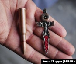 The jeweler holds a crucifix made from a sniper round.