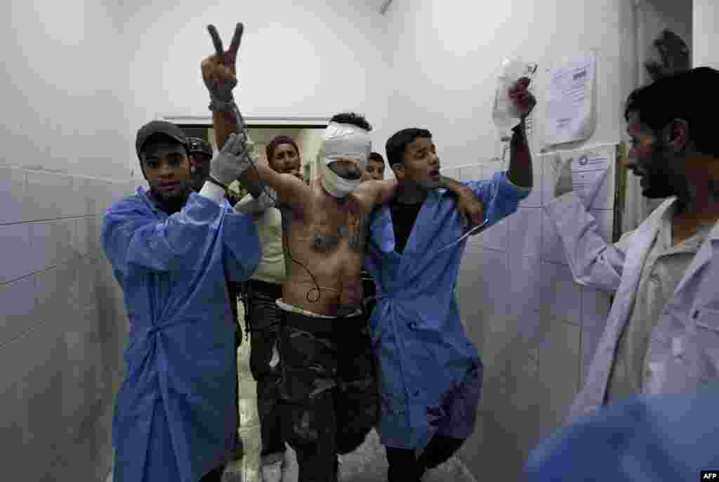 A Libyan rebel wounded during fighting for control of the town of Brega flashes a victory sign as he is rushed into the emergency room at the general hospital in Ajdabiya on July 17.Photo by Gianluigi Guercia for AFP