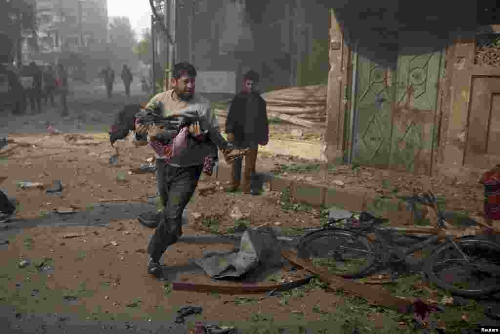 A man carries an injured girl as he rushes away from a site hit by what activists said were air strikes by forces loyal to Syria's president, in the Douma neighborhood of Damascus. (Reuters/Bassam Khabieh)