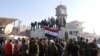 Government soldiers and civilians gather as they place the Syrian national flag on a truck in Qusayr on June 5.