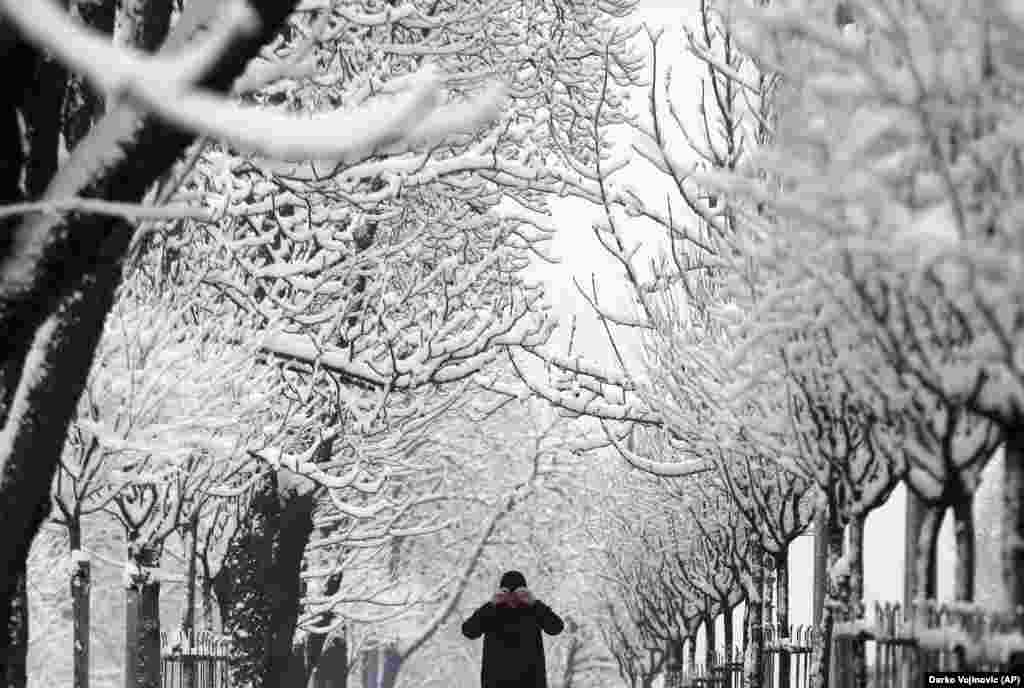 A man adjusts his hat on a snow-covered street in Belgrade. Meteorologists predict heavy snowfall and subzero temperatures in Serbia throughout the week. (AP/Darko Vojinovic)