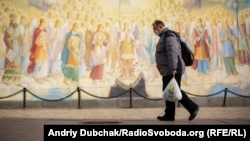 Мужчина в медицинской маске идет возле Михайловского Златоверхого собора в Киеве, который принадлежит Православной церкви Украины.