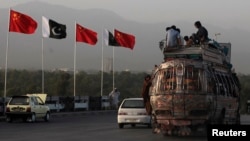 People sit atop a bus as they pass Chinese and Pakistani flags in Islamabad ahead of a trip by Chinese Prime Minister Li Keqiang in 2013.