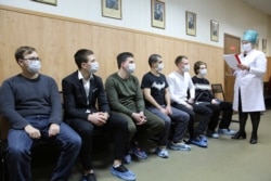 A group of Russian conscripts, wearing face masks for protection against the coronavirus, wait for a medical checkup at a military conscription office in Moscow.