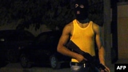 Libya -- A masked Libyan gunman stands on a street in the eastern city of Benghazi, early on July 29, 2014, as violence has hit the city.