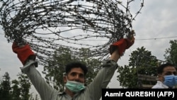 A plain cloth policeman carries barbed wire to seal a street at Aabpara commercial and residential area in Islamabad on June 24, as COVID-19 coronavirus cases continue to rise. 