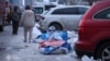 A photo released by the press service of Ukraine's Emergency Service shows a resident sitting on the ground, covered with blankets, at the site of an apartment building hit by a Russian drone in Kyiv, Ukraine, on December 27.
