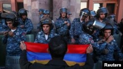 Un protestatar cu un steag armean în fața ofițerilor de poliție, în timpul unei demonstrații în sprijinul armenilor din Nagorno-Karabah, Erevan, Armenia, 20 septembrie 2023. 