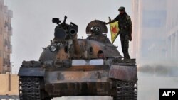 A fighter from the Kurdish People's Protection Units (YPG) drives a tank in the Al-Zohur nieighborhood in the Syrian city of Hasakeh.