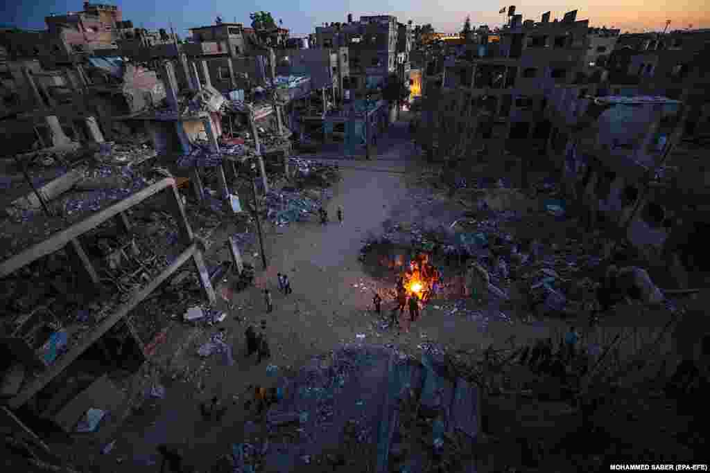 Palestinezët mblidhen rreth një zjarri pranë shtëpive të tyre të shkatërruara në, Beit Hanoun, në veri të Rripit të Gazës. 26 maj, 2021.