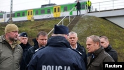 Polish Prime Minister Donald Tusk (right) surveys the site of damaged railway tracks on the Warsaw-Lublin line on November 17 in Mika after an explosion that he called an "unprecedented act of sabotage."