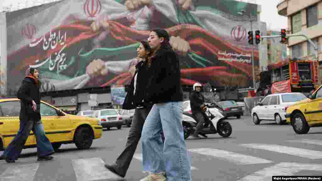 Žene hodaju centralnim Trgom revolucije u Teheranu. Na transparentu u pozadini piše: "Iran je naša zemlja, njegova zastava je naš pogrebni pokrov."