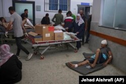 Stafi i spitalit Shifa duke bartur kuti me furnizime pranë Yousef Abu Suhailas, 16 vjeç, i cili u plagos nga një sulm ajror izraelit dhe priste të trajtohej.