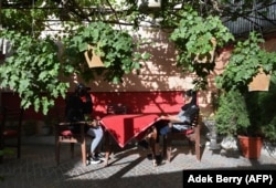 Young people sit at a sidewalk cafe in Kabul on June 19.