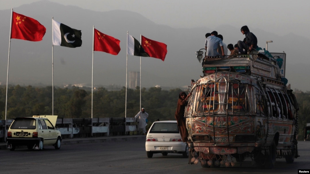 People sit atop a bus as they pass Chinese and Pakistani flags in Islamabad ahead of a trip by Chinese Prime Minister Li Keqiang in 2013.