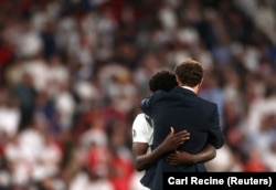 Managerul echipei Marii Britanii, Gareth Southgate, îl consolează pe Bukayo Saka după ce jucătorul a ratat lovitura de departajare la finala Euro 2020