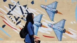 An Iranian woman walks next to an anti-Israeli mural on a street in Tehran on May 26. 