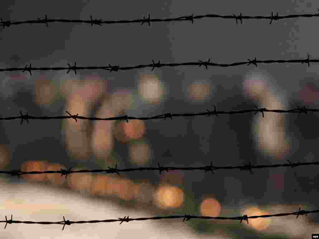 People light candles near the barbed-wire fences of the Nazi concentration camp at Auschwitz-Birkenau. - Survivors, dignitaries, and others on January 27 marked the 65th anniversary of the Red Army's liberation of the death camp in Poland where more than 1 million people died during World War II. Photo by Radek Pietruszka for epa