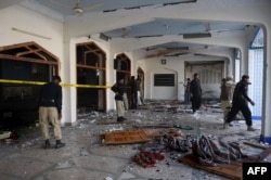 Pakistani security personnel inspect the Shi'ite Muslim mosque after the attack.