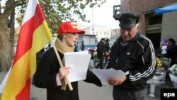 Georgia/South Ossetia -- An activist of South Ossetian youth organization hands leaflets to an elderly Ossetian man, Tskhinval, 09Nov2006