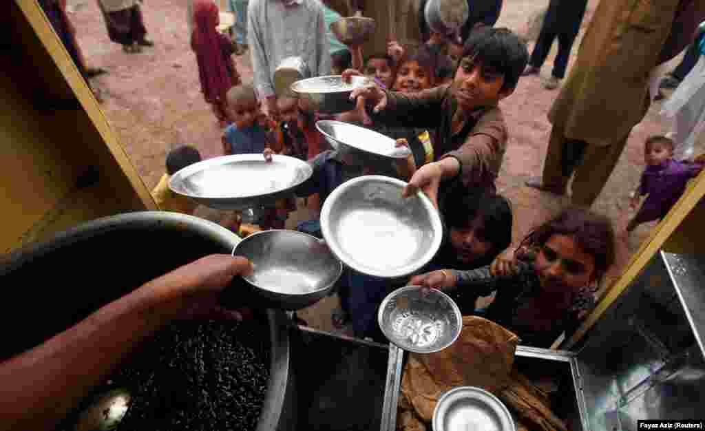 Pakistanyň Peşewar şäherinde çagalar haýyr-sogap hökmünde berilýän nahary almak üçin gaplaryny uzadýarlar. (Reuters/ Fayaz Aziz)