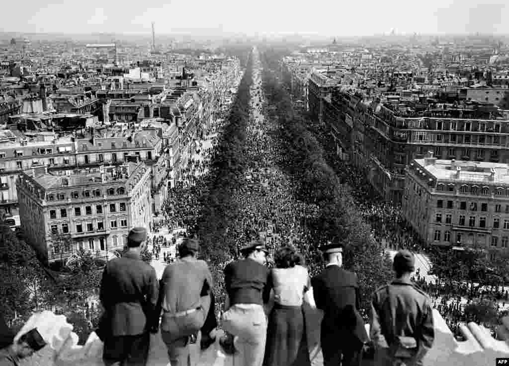 A group watches from the top of Paris&#39;s Arc de Triomphe as crowds gather.