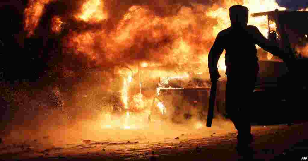 Ukraine -- A protester stands next to a bus in flames as protesters clash with riot police, Kyiv, 19Jan2014