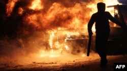 Ukraine -- A protester stands next to a bus in flames as protesters clash with riot police, Kyiv, 19Jan2014