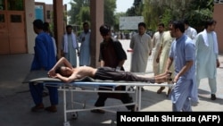 Afghan volunteers carry an injured youth on a stretcher to a hospital following an attack that targeted an education department compound in Jalalabad on July 11.