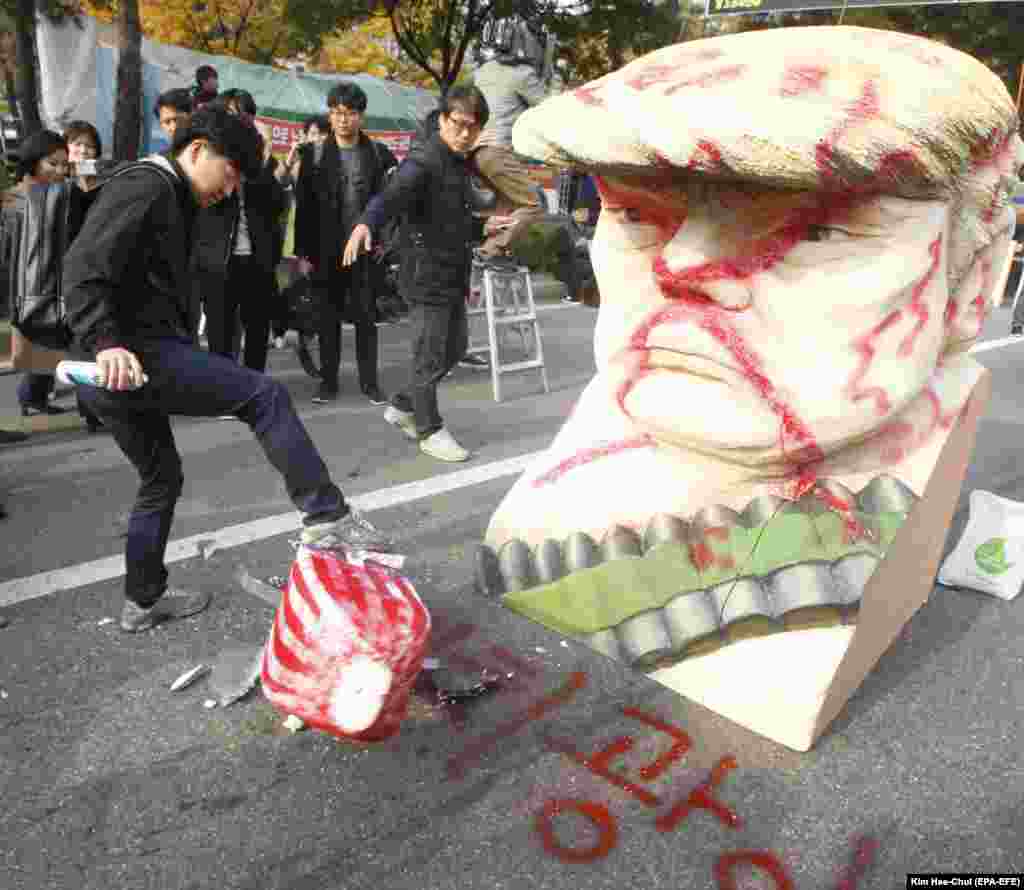 A South Korean protester kicks a mock rocket after spray painting the word "lunatic" next to a bust resembling U.S. President Donald Trump during a rally held to show opposition to Trump's visit to South Korea, near the National Assembly in Seoul on November 8. (epa-EFE/Kim Hee-chul)