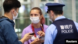 Belarusian athlete Krystsina Tsimanouskaya talks with a police officer at Haneda airport in Tokyo on August 1.