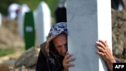 Bosniýaly zenan Srebrenisa gyrgynçylygynda heläk bolan we jesetleri täze tapylan 775 adamyň jaýlanyş çäresinde mazar daşyny gujaklaýar, Bosniýa-Gersogowina, 11-nji iýul, 2010-njy ýyl.