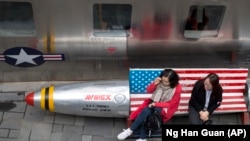 АҚШ-тан әкелінген киімдер сатылатын дүкеннің қасында отырған адамдар. Пекин, 23 наурыз 2018 жыл.