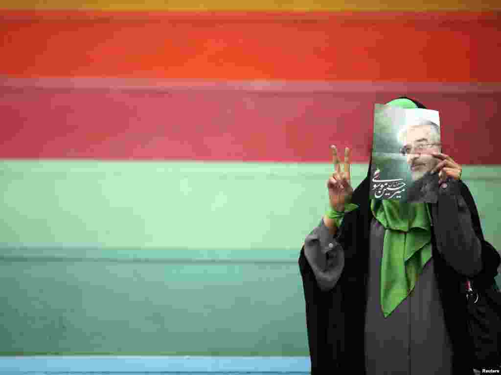 An Iranian woman supporting former prime Minister Mirhossein Mousavi, who is a candidate for the upcoming presidential elections, covers her face with his picture during a pre-election gathering at a stadium in Tehran June 9, 2009. REUTERS/Damir Sagolj