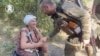 Un membru al Brigăzii 47 Mecanizate Separate vorbind cu o femeie din zona eliberată, în Robotine, în regiunea ucraineană Zaporojie, pe 22 august.