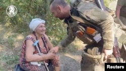 Ukrán katona fog kezet egy helyi nővel Robotyinéban 2023. augusztus 22-én
