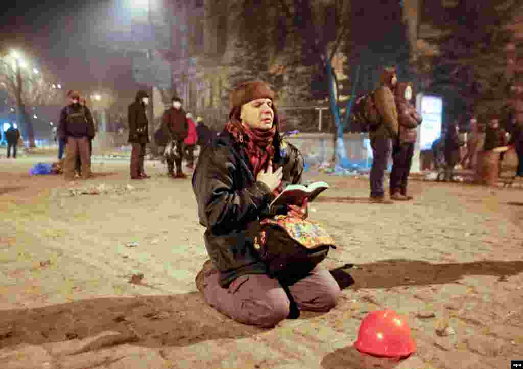 A protester prays as he holds an open Bible during an antigovernment protest in downtown Kyiv on January 21. (EPA/Serghey Dolzhenko)