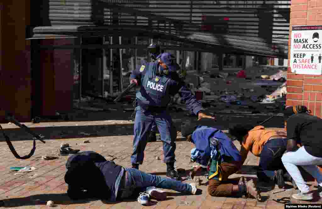 Oficerët policorë arrestojnë demonstrues teksa protestat vazhdojnë, pas burgosjes së Zumas. (Katlehong, 12 korrik)