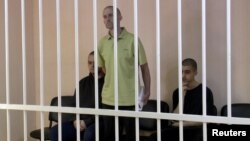 Британцы Эйден Эслин (слева), Шон Пиннер (в центре) и гражданин Марокко Брагим Саадун Брагим (справа) в «суде» вооруженной группировки «ДНР», контролируемой Россией. Оккупированный Донецк, 7 июня 2022 года