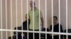 A still image shows Britons Aiden Aslin (left), Shaun Pinner (center), and Moroccan Brahim Saadoun appear in a courtroom cage at a location said to be Donetsk.