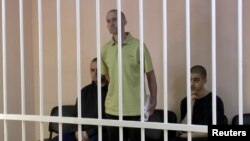 Британці Ейден Еслін (ліворуч), Шон Піннер (посередині) та громадянин Марокко Брагім Саадун (праворуч) у так званому «суді» проросійського угруповання «ДНР». Окупований Донецьк, 7 червня 2022 року 